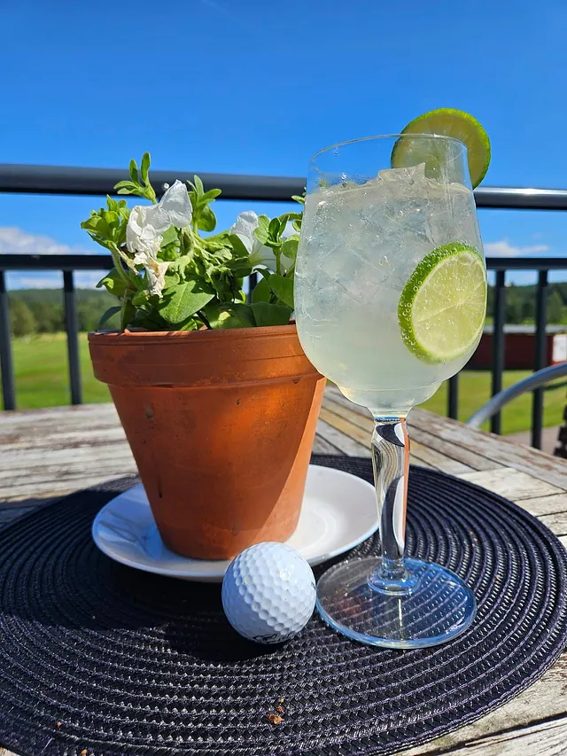 Dryckesglas på en veranda, en golfboll med en vit blomma i terracottakruka